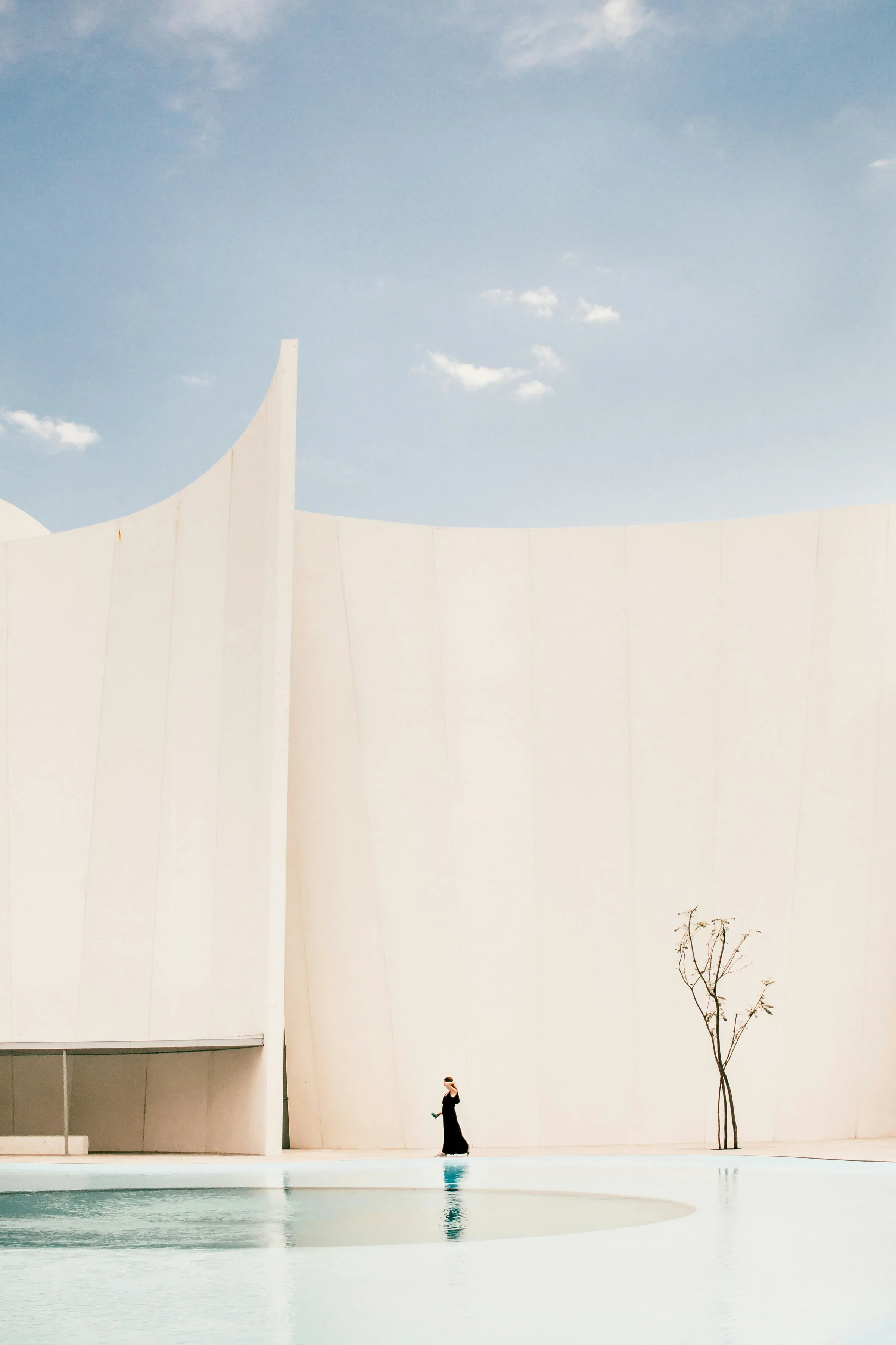 Sweeping white concrete wall curving against a clear sky